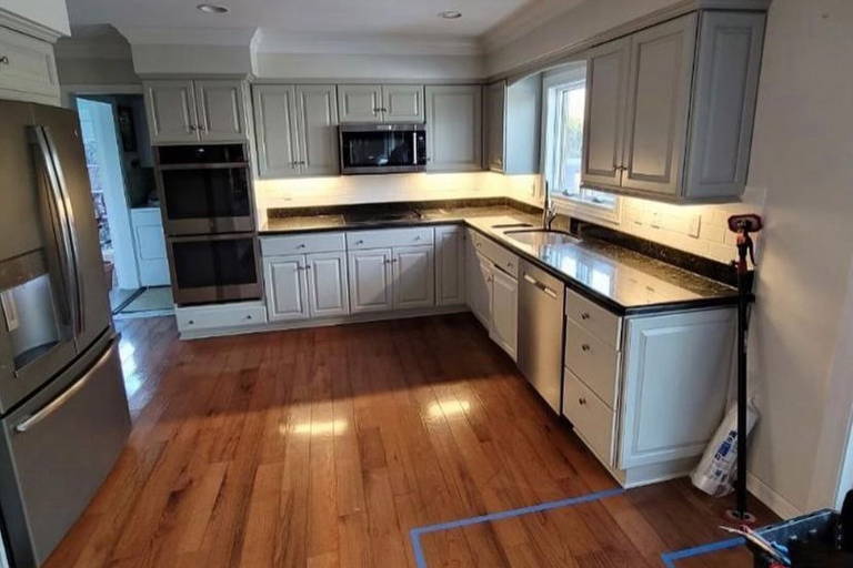 Kitchen with stainless steel appliances, black countertops, and wooden flooring.